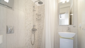 Un bagno moderno con doccia, toilette, lavabo e specchio.