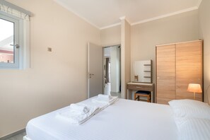 Une chambre d’hôtel avec un lit, un bureau, une armoire et une salle de bain, visibles à travers une porte ouverte.