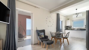 A modern kitchen with a dining area, a TV mounted on the wall, and a large window.
