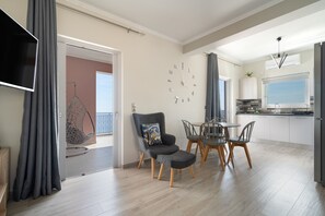 A modern kitchen with a dining area, a TV mounted on the wall, and a large window. - Seaside Retreat with Stunning Sea Views in Kefalonia (Vlachata)