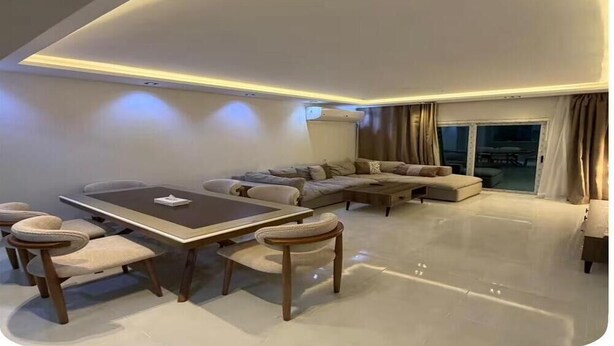 Un salón moderno con una mesa de comedor, sofás y un ventanal grande.