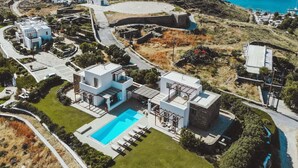 En modern villa med en swimmingpool, omgiven av en vackert anlagd trädgård och med utsikt över havet.