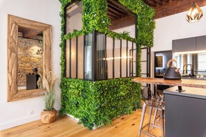 A kitchen with a wooden counter, bar stools, a kettle, and a stone wall. - Les Balcons de Guignols - Premium apartment in the center of town (Lyon)