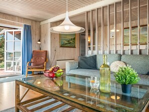 Ein modernes Wohnzimmer mit Glastisch, Ledersessel, grauem Sofa und einem Gemälde an der Wand.