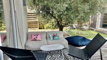 Eine Terrasse mit einer Sitzecke, zwei Stühlen, einem kleinen Tisch und einem gemusterten Teppich.
