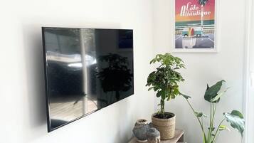 Ein modernes Wohnzimmer mit einem flachbildfernseher an der Wand, einem Holzkonsolentisch mit Dekoration und einem Poster.
