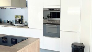 Et moderne køkken med hvide skabe, en sort bordplade og rustfrie stålgrejs.