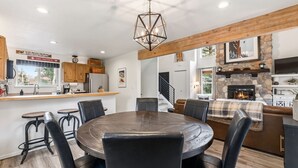 A spacious kitchen with a central island, wooden beams, a stone fireplace, and a dining area with a round table and chairs. - Renovated Frisco Retreat Near Main St & 4 Ski Resorts (Frisco)