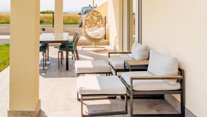Une terrasse avec un espace salon extérieur comprenant un canapé, des fauteuils et un fauteuil suspendu.