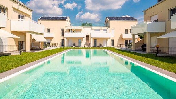 Un immeuble résidentiel moderne doté d’une piscine, de balcons et de panneaux solaires.