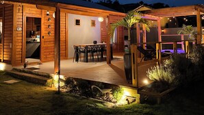 Una cabaña de madera con un porche, mobiliario exterior y una pequeña cocina.