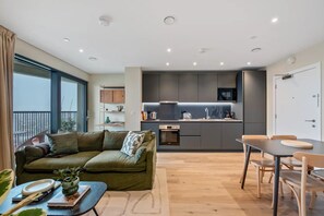 Eine moderne Wohnung mit Wohnbereich, Küchenzeile und Essplatz.