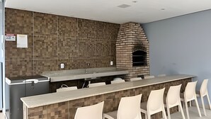 Een moderne keuken met een ingebouwde bakoven, een lange aanrecht met stoelen, en een betegelde spatwand.