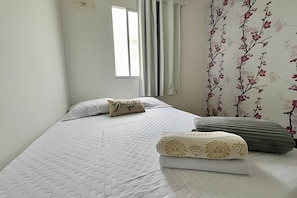A neatly made bed with a quilted pattern, a pillow with a floral design, and a decorative pillow with a gold pattern.