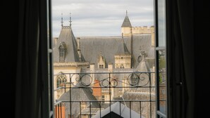 A view through a window with a wrought iron railing, featuring a historic building with multiple pointed roofs and a prominent tower. - Hotel & Spa des Beaux-Arts Bourges, a member of Radisson Individuals (Bourges)