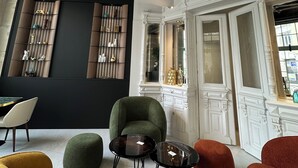 A room with a high ceiling featuring ornate plasterwork, a fireplace, and a seating area with colorful sofas and a small round table. - Hotel & Spa des Beaux-Arts Bourges, a member of Radisson Individuals (Bourges)
