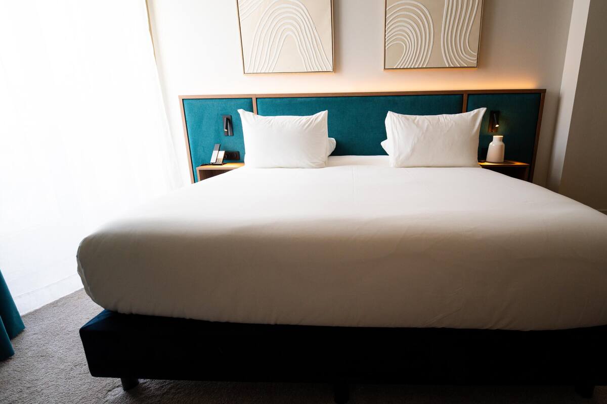 Una habitación de hotel con una cama grande, dos mesitas de noche y obras de arte en la pared.