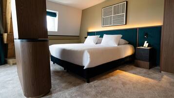A hotel room with a bed, a nightstand, a wall-mounted artwork, and a window.