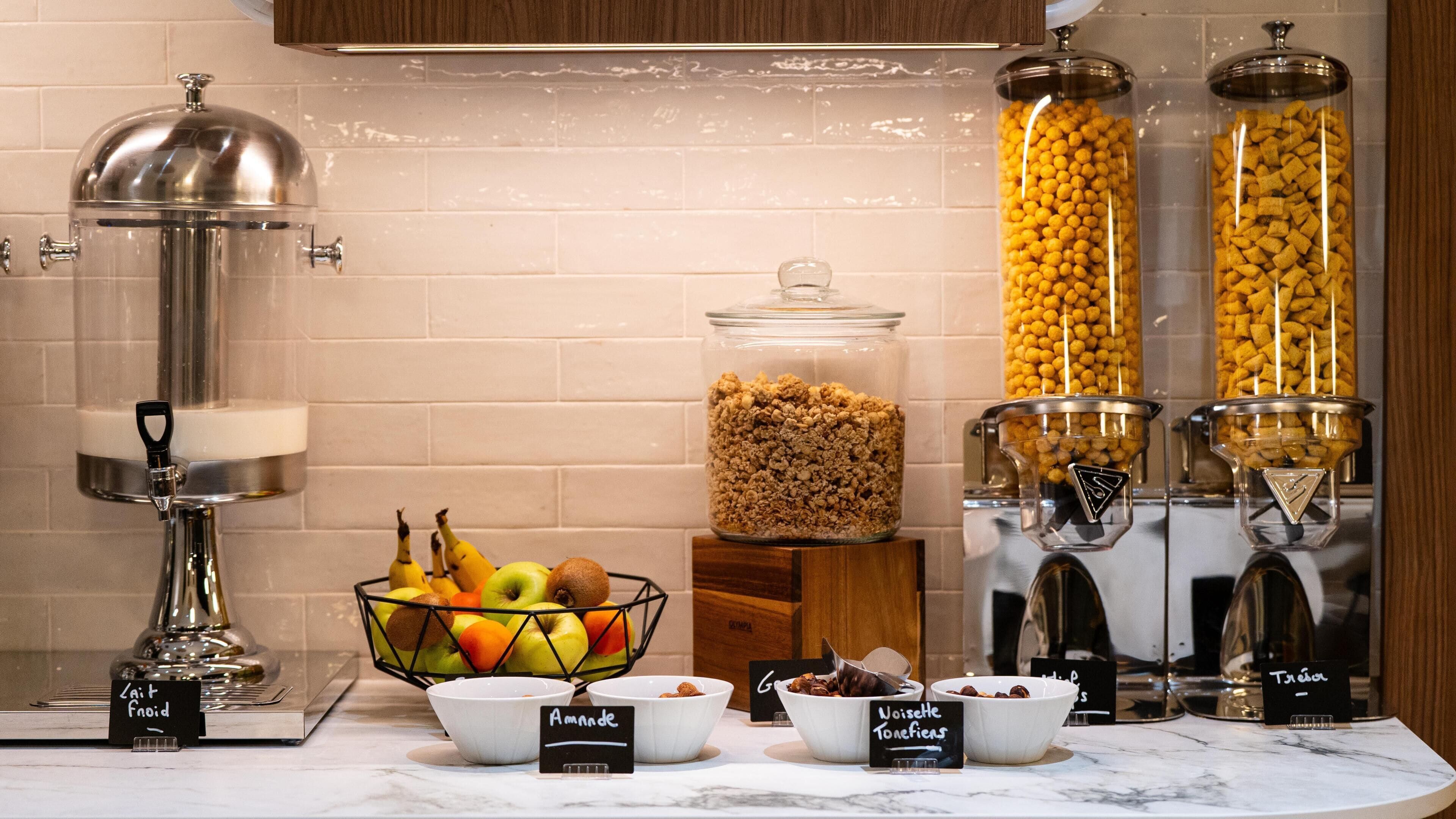 Un bufé de desayuno con diversas opciones de alimentos, entre ellas frutas, cereales y frutos secos.