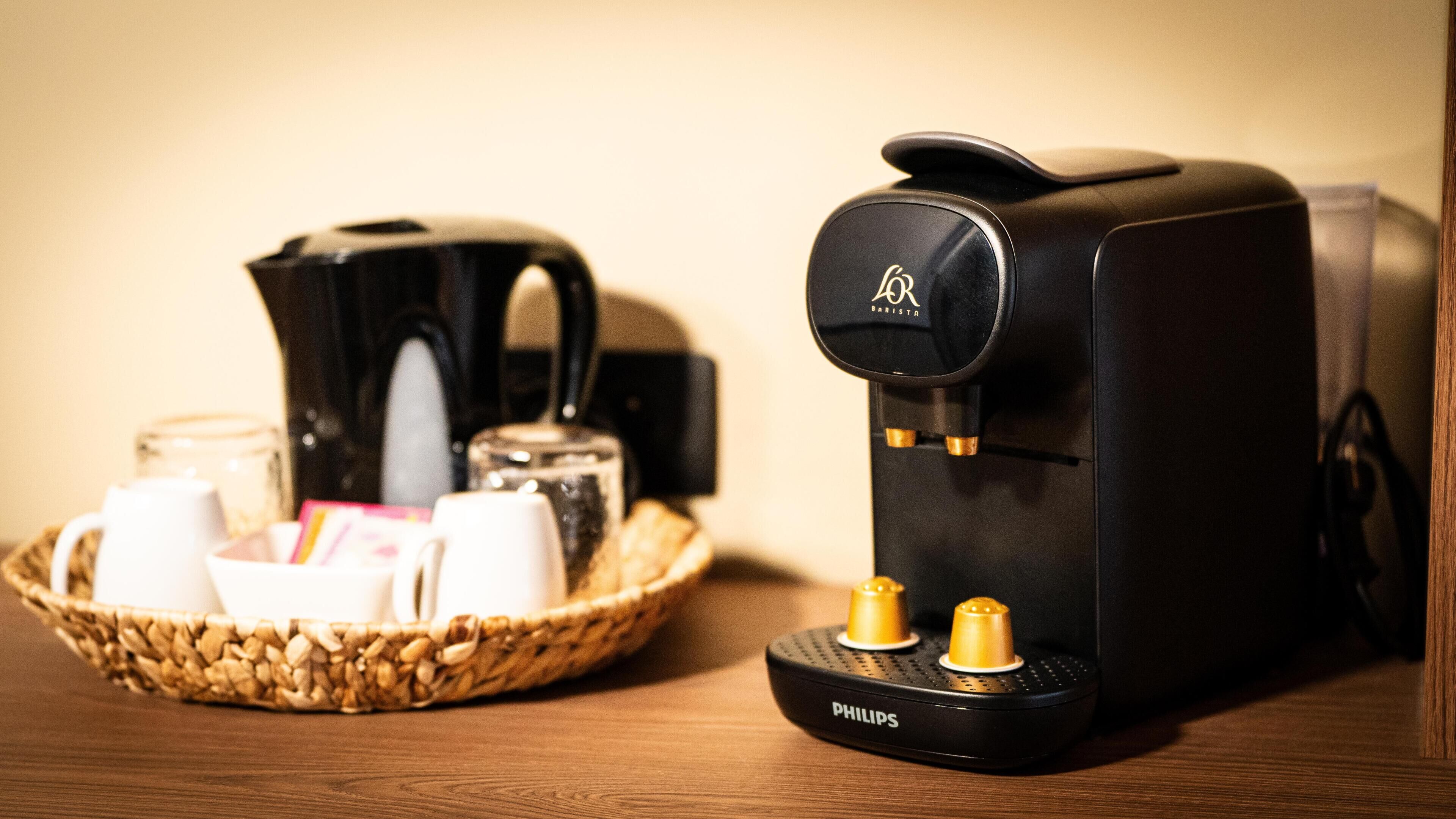 Une machine à café et un panier contenant des tasses à café et une théière, le tout posé sur une surface en bois.