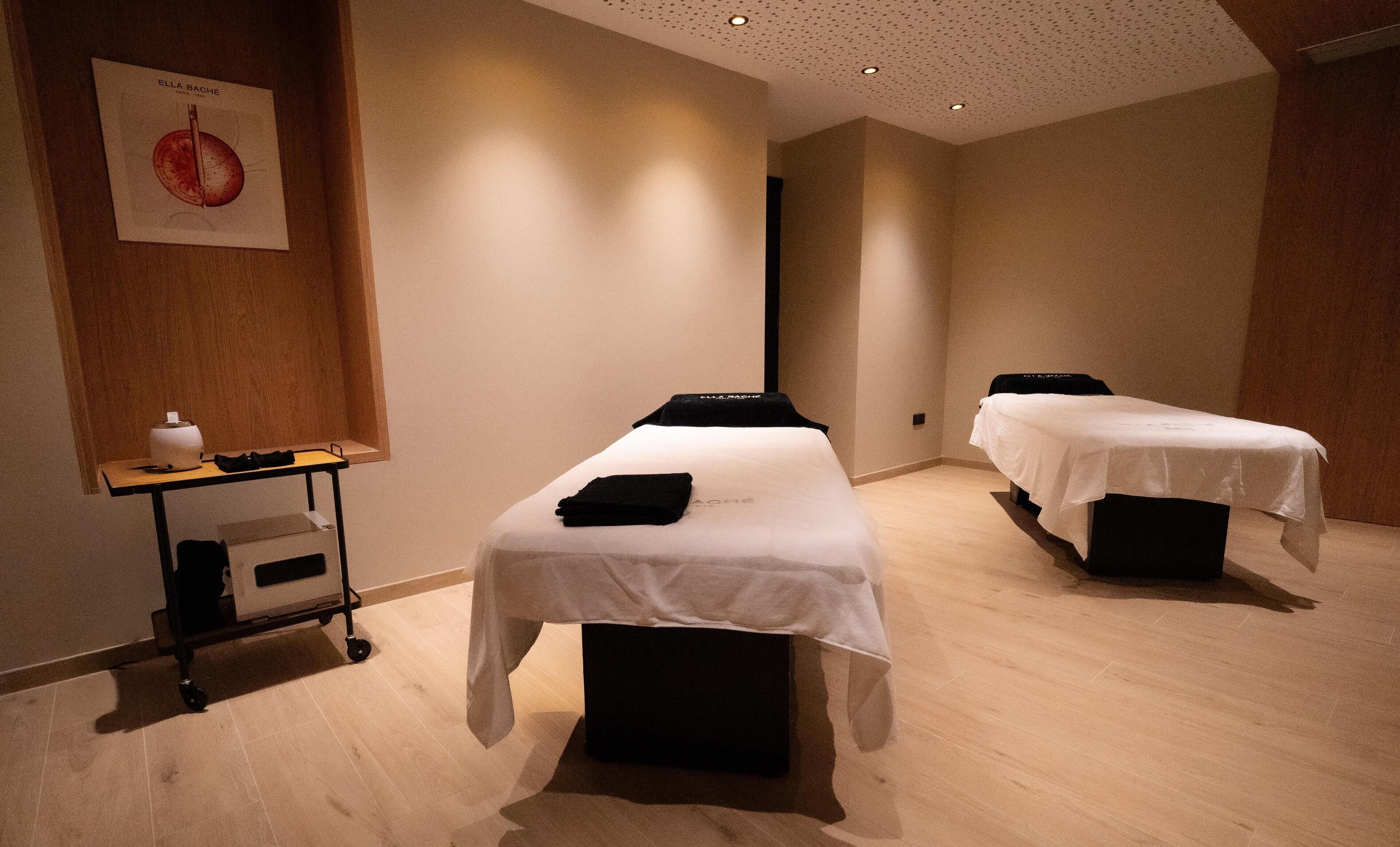 A room with two beds, a small table with a lamp, and a poster on the wall.