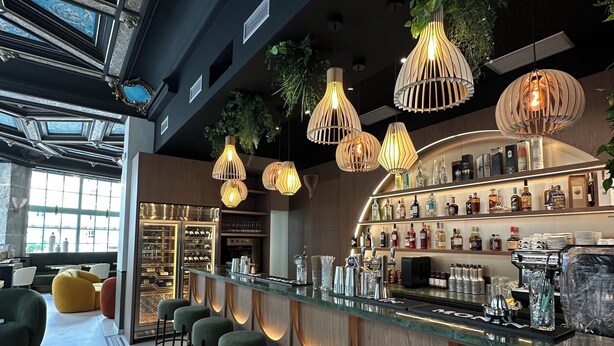 A bar area with a long counter, multiple stools, hanging light fixtures, and shelves with bottles. - Hotel & Spa des Beaux-Arts Bourges, a member of Radisson Individuals (Bourges)