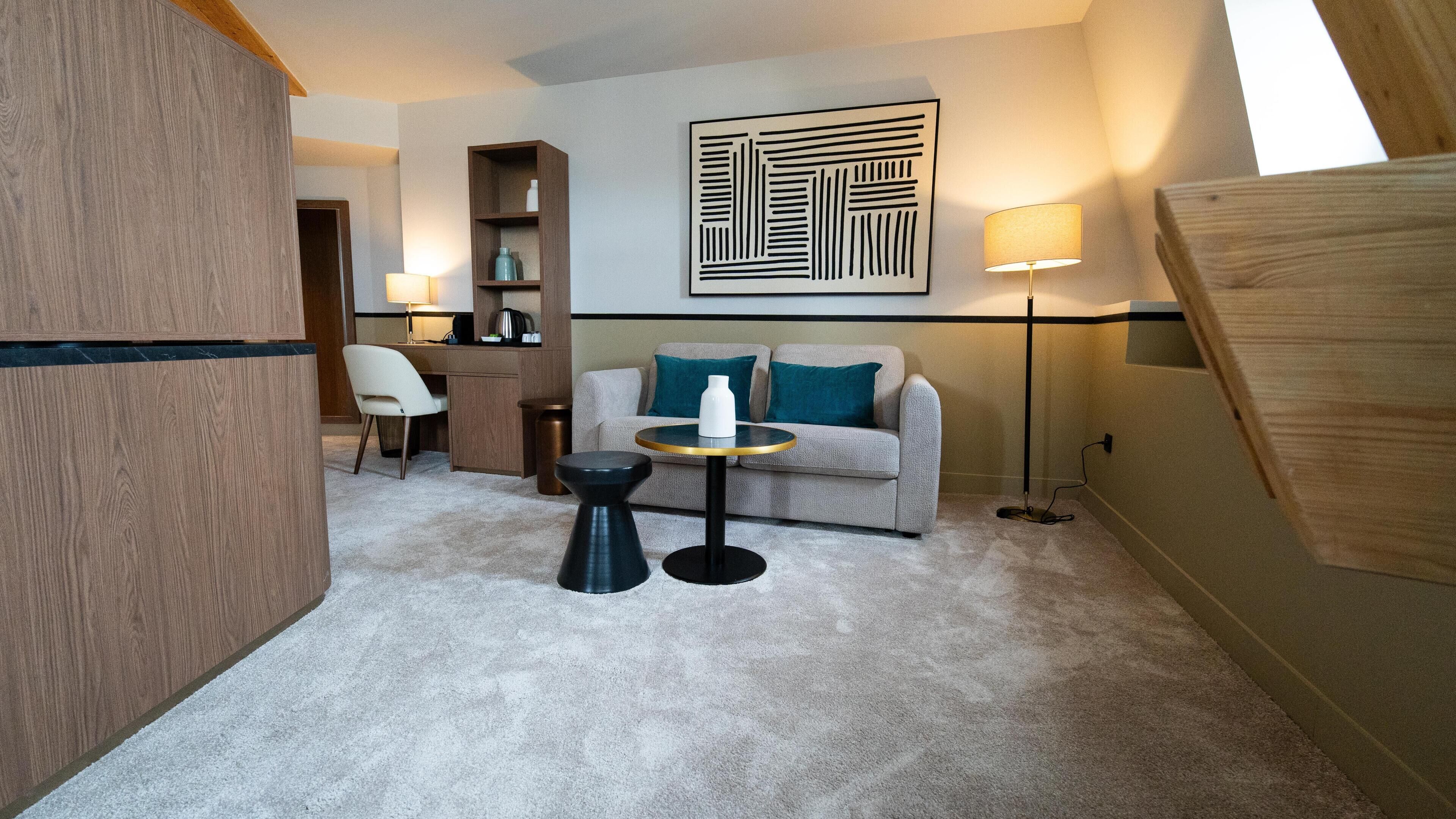 A modern living room with a sofa, a coffee table, a chair, a desk, and a bookshelf.