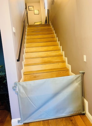 Eine Holztreppe mit Handlauf, die zu einer Zwischenebene mit gerahmten Bildern führt.