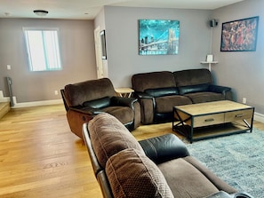 Ein Wohnzimmer mit einer Couch, einem Relaxsessel, einem Couchtisch und Kunstwerken an den Wänden.