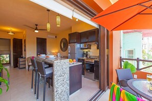 A modern kitchen with granite countertops, a built-in oven, and a dining area with wicker chairs. - Beach Break Suites, 1 BR Suites Just Steps from Sayulita's Action (Sayulita)