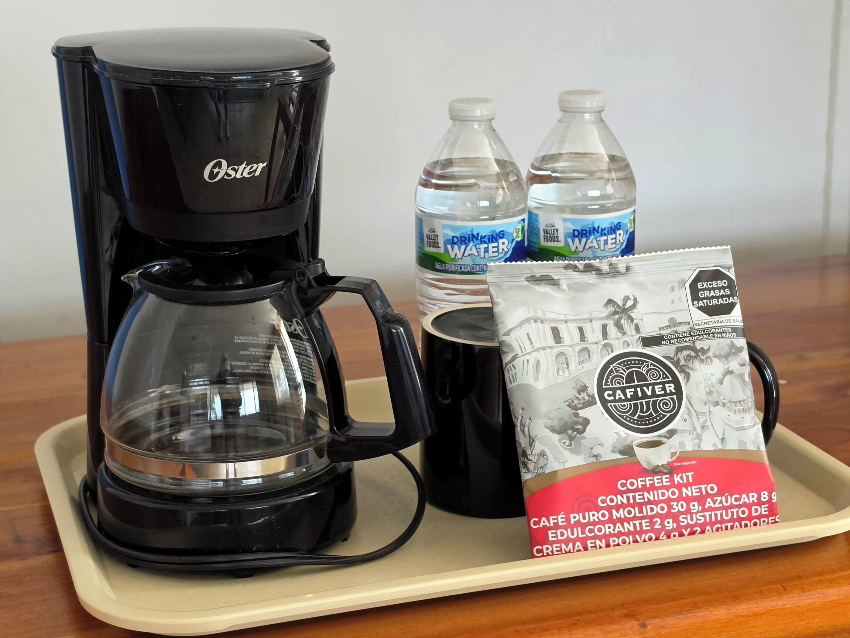 Una macchina da caffè, due bottiglie d'acqua e un set per preparare il caffè su un vassoio.