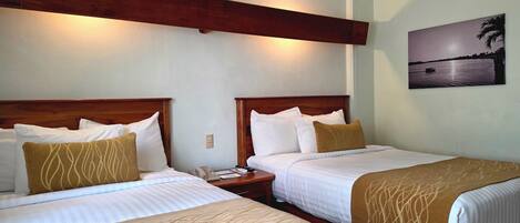 Two beds with wooden headboards, white bedding, and a nightstand with a phone and remote control.