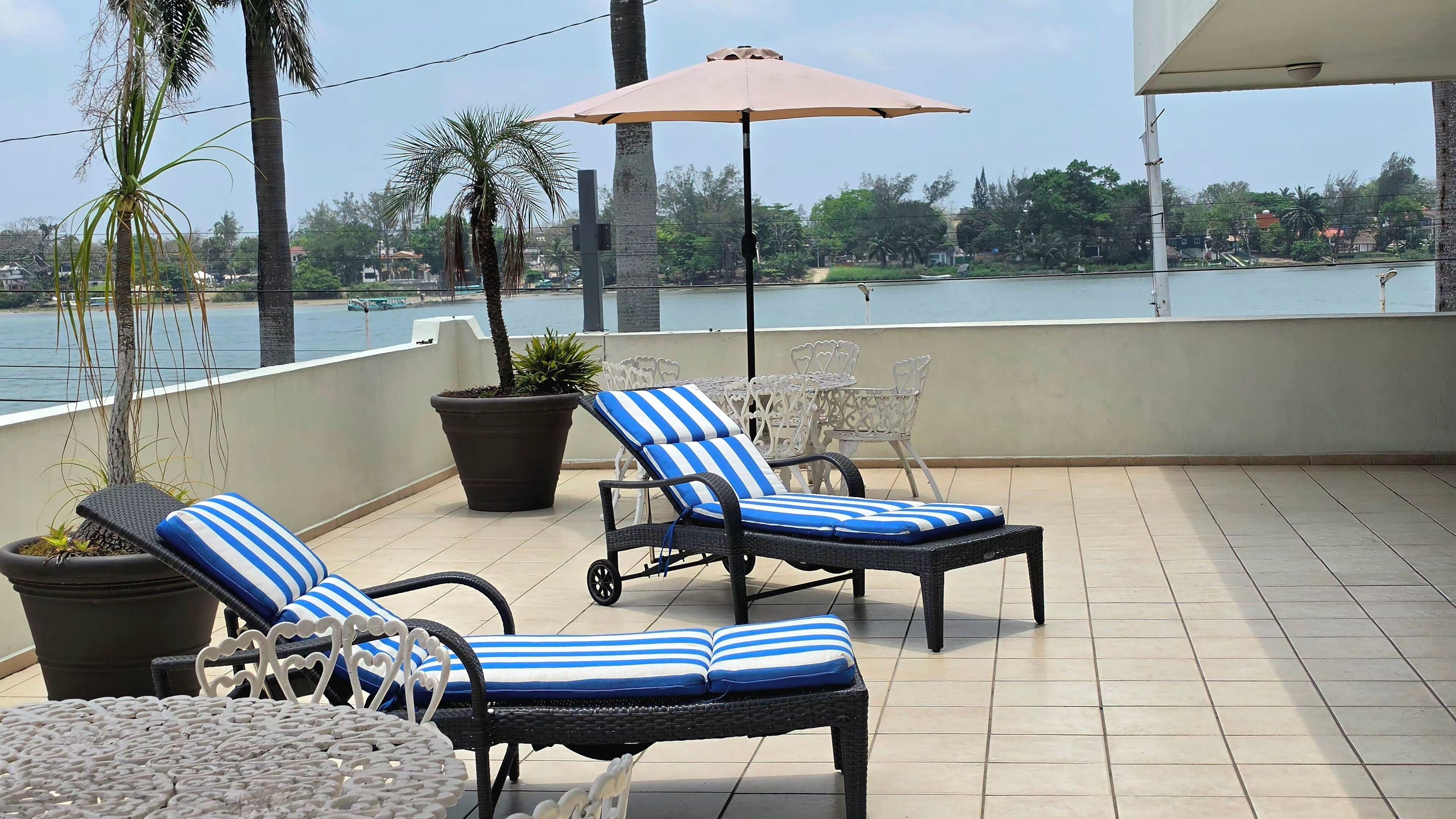 A balcony with two lounge chairs, a table, and a potted plant.