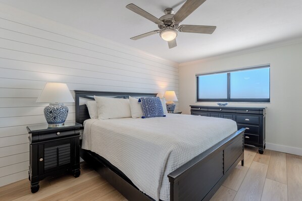 Quarto com uma cama, duas mesas de cabeceira, um ventilador de teto, uma janela e um armário.