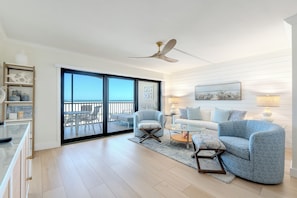 Ein modernes Wohnzimmer mit Balkon, Deckenventilator und Meerblick.