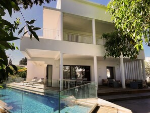 A modern two-story house with a glass-enclosed swimming pool, outdoor seating, and a balcony. - Carthage Villa | 3BR Luxury · Pool · Garden (Carthage)