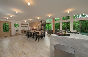 Ein geräumiger Essbereich mit einem Holztisch und Stühlen, einer Treppe und großen Fenstern mit Blick ins Freie.