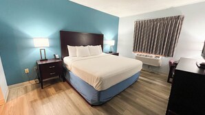 A hotel room with a bed, bedside lamps, a desk, and a window with curtains. - Studio 6 Suites – Tiffin, Oh (Tiffin)