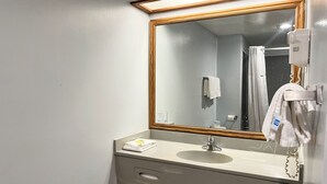 A bathroom with a mirror, sink, towel rack, and a shower curtain. - Studio 6 Suites – Tiffin, Oh (Tiffin)
