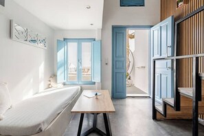 A modern room with a bed, a table, and a view of the outside. - Simplicity Suite, Sea view, cosy place near Fira Center, high speed internet! (Fira)