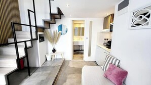 A modern interior with a staircase, a dining area, a kitchen, and a living room with a sofa. - Simplicity Suite, Sea view, cosy place near Fira Center, high speed internet! (Fira)