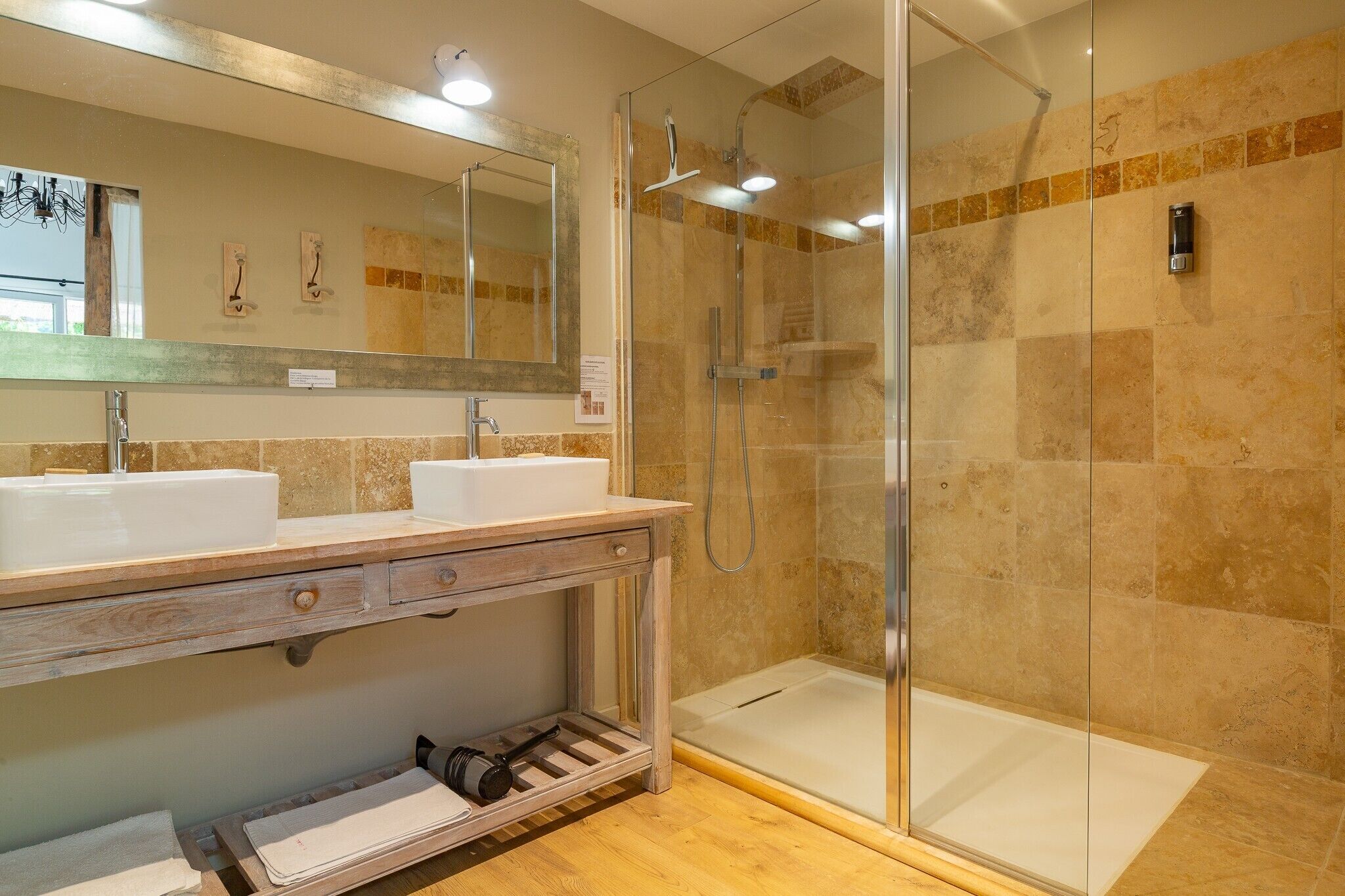 A bathroom with two sinks, a mirror, a shower, and a towel rack.
