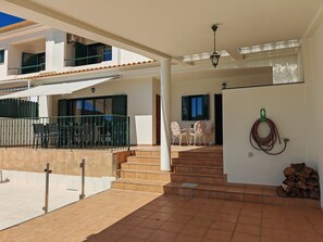 Un bâtiment à deux étages doté d’un balcon, d’un espace extérieur aménagé pour s’asseoir et d’un escalier menant à l’étage supérieur.