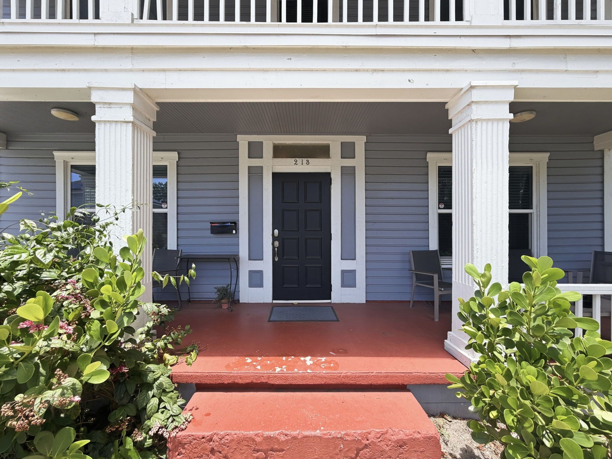 A two-story house with a front porch, a black front door, and a mailbox.