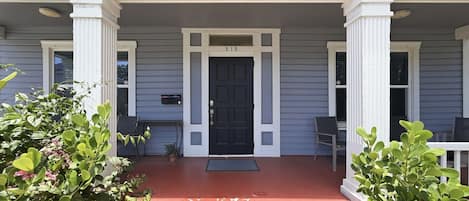 A two-story house with a front porch, a black front door, and a mailbox.