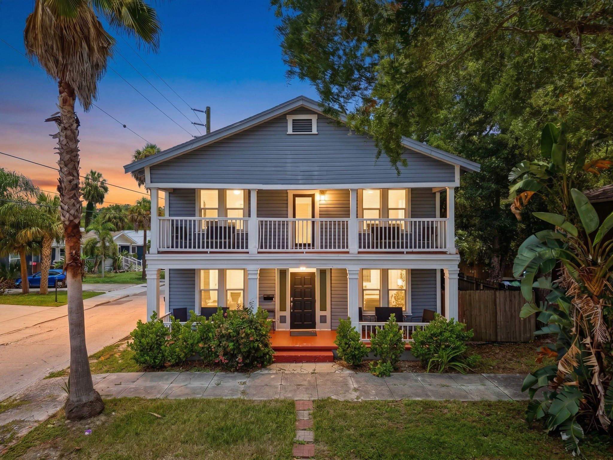 A two-story house with a front porch, a balcony on the upper floor, and a small front yard.
