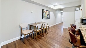 A dining area with a wooden table and chairs, a painting on the wall, and a kitchen area with a microwave. - Tampa Heights 2BR Near Riverwalk (Tampa)