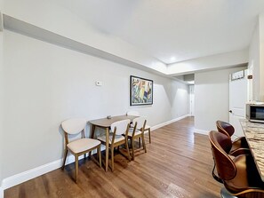 A dining area with a wooden table and chairs, a painting on the wall, and a kitchen area with a microwave. - Tampa Heights 2BR Near Riverwalk (Tampa)