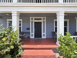 A two-story house with a front porch, a black front door, and a mailbox. - 2BR Tampa Heights Apt | Balcony, Parking, WiFi (Tampa)