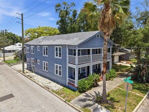 A two-story house with a balcony, a palm tree in the front yard, and a street sign. - 2BR Tampa Heights Apartment with Balcony & Parking (Tampa)